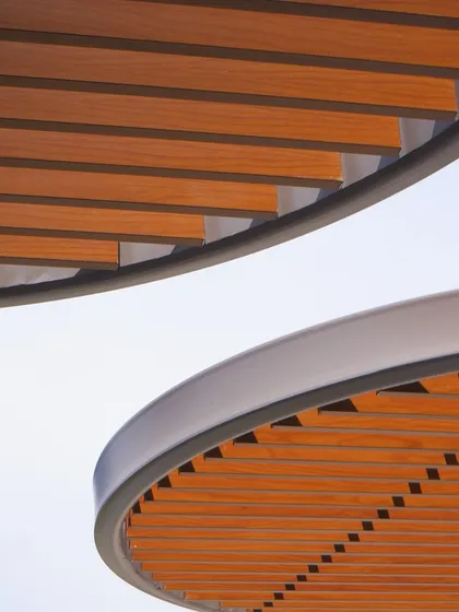 A detail shot of the curved wooden slats on the pergolas at KRC Commerzone. This demonstrates our focus on material intelligence and craftsmanship, where every element is carefully considered for both its functional performance and its aesthetic contribution.