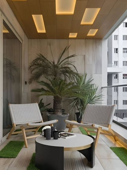 A modern and minimalist balcony design with comfortable seating and subtle floor lighting. The recessed ceiling lights add a sophisticated ambiance for evening use.