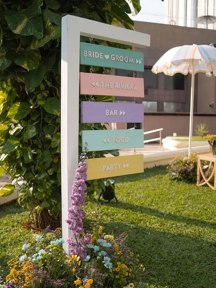 A whimsical, pastel-colored directional sign guides guests to the different areas of the French Riviera-themed party.