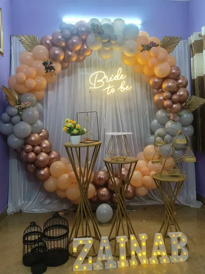 This bridal shower decor shows a softer color palette, combining peach, grey, and rose gold balloons for a sophisticated look. I included decorative props like birdcages and geometric stands to add detail, along with personalized marquee letters for the bride's name, 'ZAINAB'.