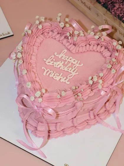 We are in love with this vintage heart-shaped cake. The soft pink frosting, delicate piping, tiny ribbons, and a sprinkle of baby's breath flowers create such a dreamy and romantic look, perfect for birthdays or bridal showers.