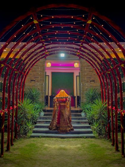 A creative shot of the bride walking through a lit archway, creating a mysterious and grand entrance photo.
