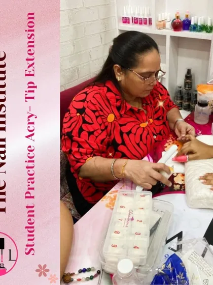 A student practices with a box of nail tips, learning how to select the right size and apply them for an acrylic extension service.