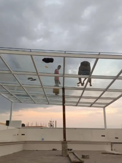 This image captures our team during the installation of a toughened glass roof on a white MS pergola frame. This option allows for maximum natural light while offering protection from rain, perfect for enjoying the sky view in any weather.