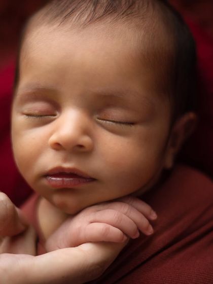 A parent's gentle hand holding their baby's chin. This shot is about connection and scale, showing just how small and protected they are in your hands.