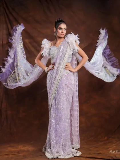 A dramatic full-length shot of a lavender saree with feathered sleeves. The pose is designed to show off the unique silhouette and intricate details of the garment.