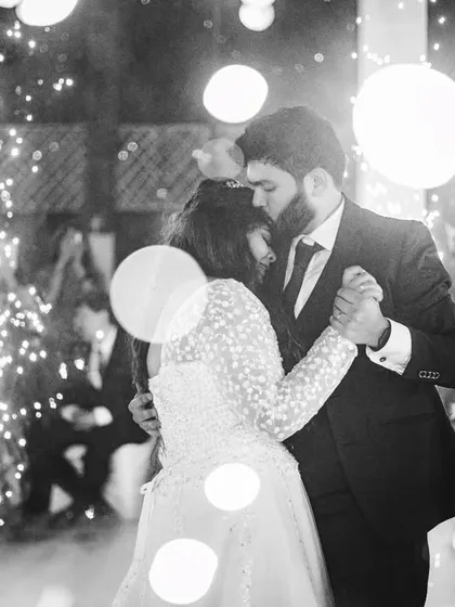 An intimate black and white photo of the couple's first dance. The use of lens flare and the surrounding sparklers creates a dreamy, romantic atmosphere, focusing entirely on their close embrace.