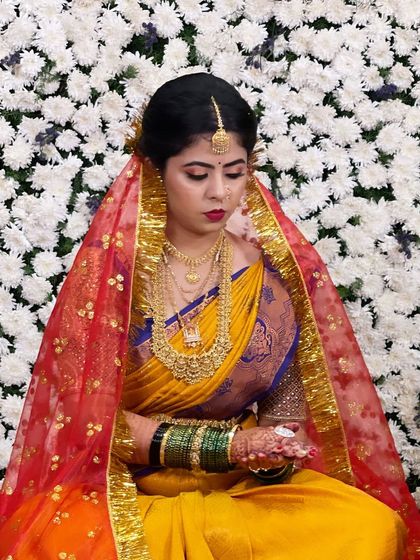 The bride during a wedding ritual, her face framed by a vibrant red veil. The makeup stands out beautifully.