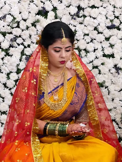 The bride during a wedding ritual, her face framed by a vibrant red veil. The makeup stands out beautifully.