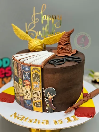 A Harry Potter book-themed cake for an 11th birthday, featuring the golden snitch and sorting hat.