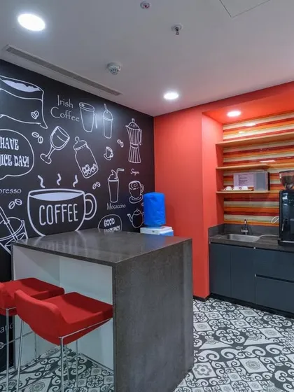 A small, cozy pantry with a chalkboard-style wall graphic featuring coffee-related illustrations. The red chairs and accent wall add a splash of color.