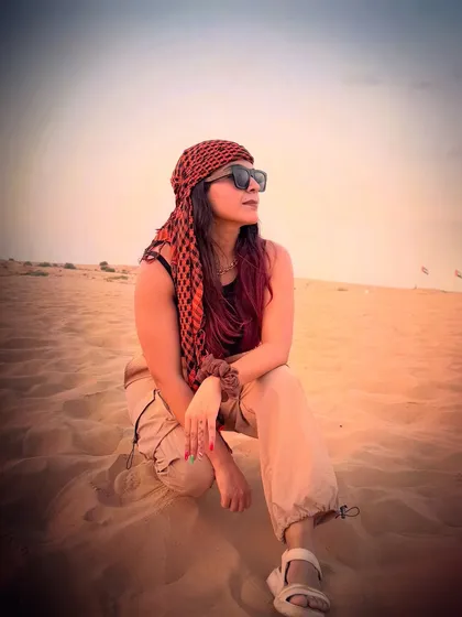A candid shot while sitting on the sand dunes. The red and black headscarf added a pop of color to my neutral-toned desert safari outfit.