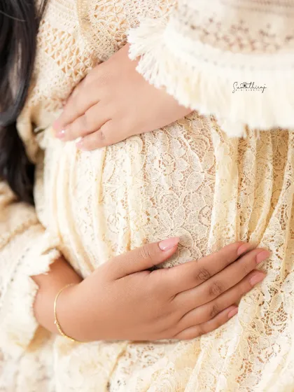A close-up shot focusing on the baby bump, draped in a delicate lace fabric. This image highlights the beautiful textures and soft, earthy feel of our boho sessions.