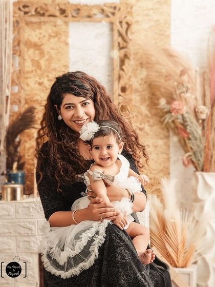 A warm and happy moment between mother and daughter. The earthy, boho-chic studio setup with dried palms and soft textures provides a beautiful, natural setting for their portrait.
