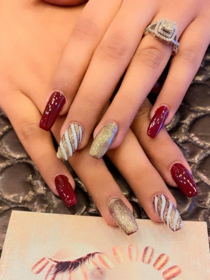 A sophisticated set of coffin nails featuring a deep red base. The accent nails include a full gold glitter nail and a white and gold striped design.