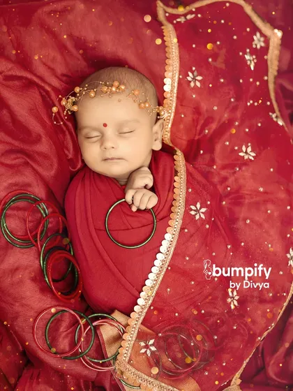 A peaceful newborn portrait for Navratri. Here, the baby is adorned with a delicate floral headband, adding a soft touch to the vibrant red traditional attire.