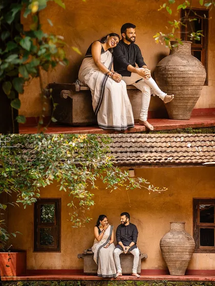 A candid, romantic moment captured at a traditional heritage home. The bride, in a classic white and black saree, rests her head on her partner's shoulder, showcasing a quiet, intimate connection in a nostalgic setting.