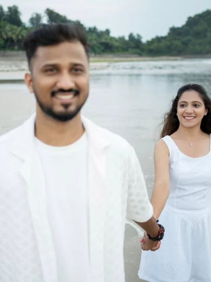 A candid walking shot on the beach, capturing a natural smile and the easy-going nature of the couple's relationship.