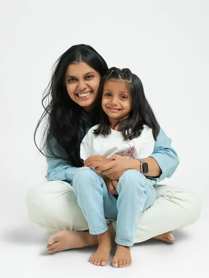A mother and daughter share a warm embrace, smiling together for the camera. This classic portrait beautifully captures their close and loving bond.