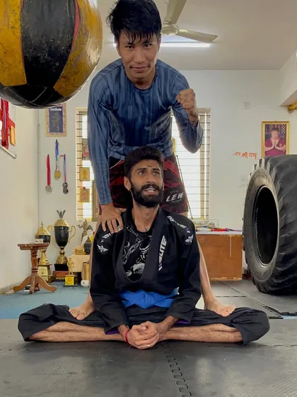A fighter's body needs to be maintained. Here, I am assisting a student with a deep stretch to improve flexibility, aid recovery, and prevent injuries, ensuring we can train consistently and hard.