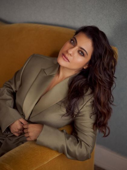 Kajol looking relaxed and elegant in an olive green satin blazer, showcasing a sophisticated yet comfortable style.