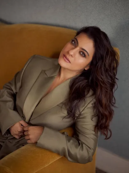 Kajol looking relaxed and elegant in an olive green satin blazer, showcasing a sophisticated yet comfortable style.