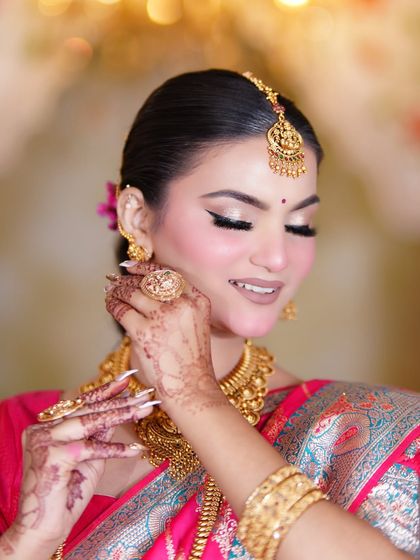 A beautiful, happy moment. The makeup is soft and glowing, enhancing her natural beauty and complementing the rich gold jewellery.