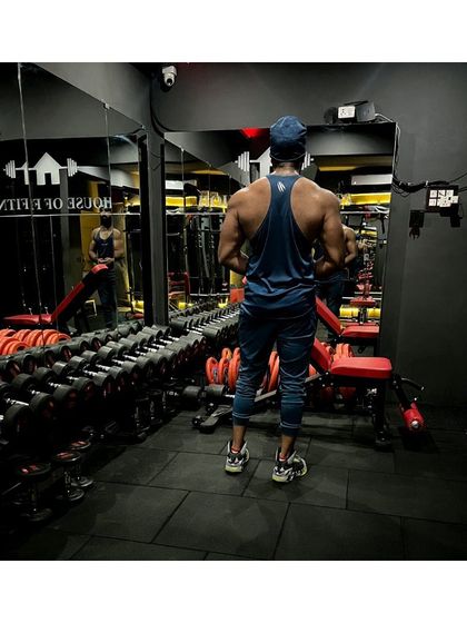 When you accept yourself, you grow. A back shot showing the results of consistent training, reflected in the mirrors of the gym.