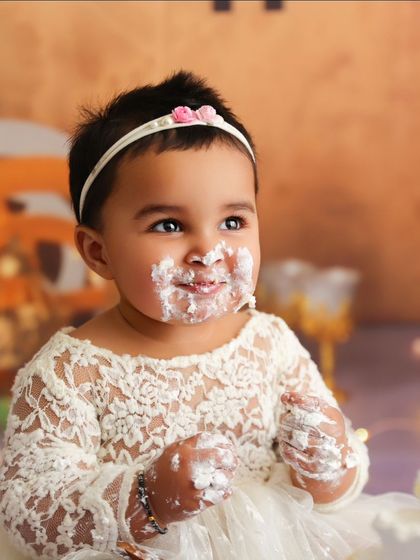 A sweet, frosting-covered smile captured during a beautifully styled cake smash session.