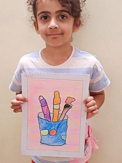 A young student shows off her colorful drawing of art supplies. It's wonderful to see them get inspired by the very tools they use to create.