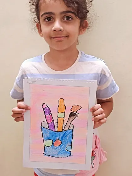 A young student shows off her colorful drawing of art supplies. It's wonderful to see them get inspired by the very tools they use to create.