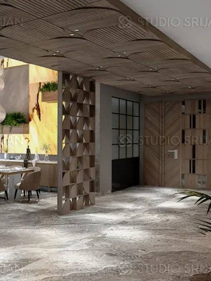 The open-plan layout of this Varanasi project shows the seamless flow from the entrance to the dining area, unified by a wood-paneled ceiling and stone flooring.