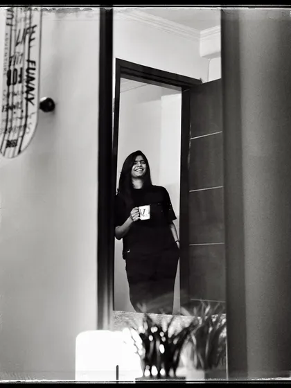 Vasu, enjoying a cup of coffee in her doorway. A simple, everyday moment that feels peaceful and content.