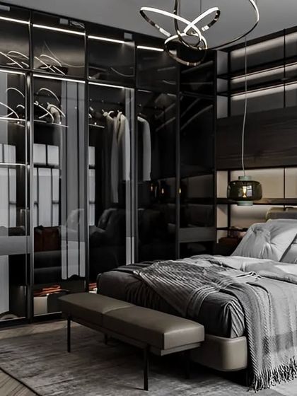 A sleek and modern bedroom featuring a walk-in closet with smoked glass doors. The dark color scheme and integrated lighting create a sophisticated, high-end hotel feel.