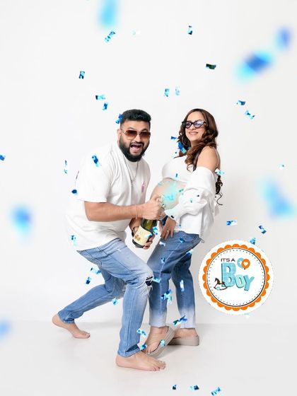 The big reveal. A shower of blue confetti celebrates the news that "It's a Boy!" during a fun and energetic casual maternity shoot.