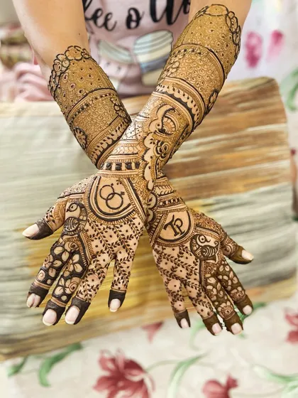 This design features the couple's initials, 'K' and 'P', inside elegant circular frames, complemented by leaf-like patterns on the fingers.
