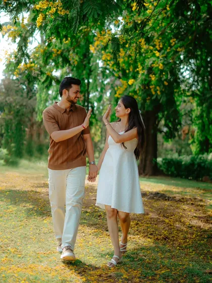 A playful high-five while walking through a park. This candid shot captures the fun and friendship in Umesh and Janhavi's relationship.