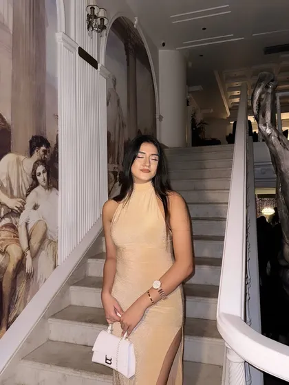 Posing on a grand staircase, the setting matches the elegance of the dress.