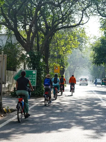 Cycling on a quiet road flanked by mature trees. We love showing our riders the green lungs of Delhi, offering a peaceful escape within the city.