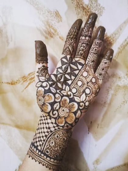 A beautiful design featuring a star-like geometric pattern in the center of the palm, surrounded by florals. The wrist cuff has a lovely checkerboard pattern, adding to the detail.