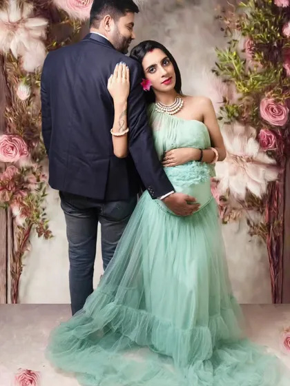 An intimate couple maternity pose against a soft, floral background, highlighting the bond between the parents-to-be.