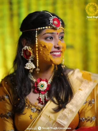 The Haldi glow is real. This bride's smile is made even brighter by the custom red and white floral jewellery I designed for her, including a traditional matha patti.