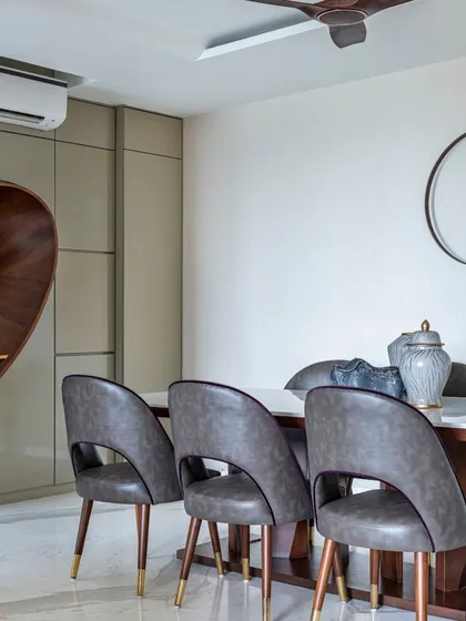 A focused view of the dining area in the Filigree House. The clean lines of the table and chairs are complemented by the sculptural wooden element, creating a space that is both modern and warm.