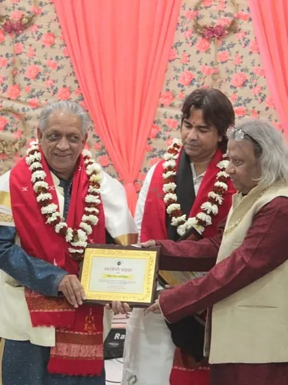 A senior artist being felicitated by another great musician, a moment of mutual respect and admiration.
