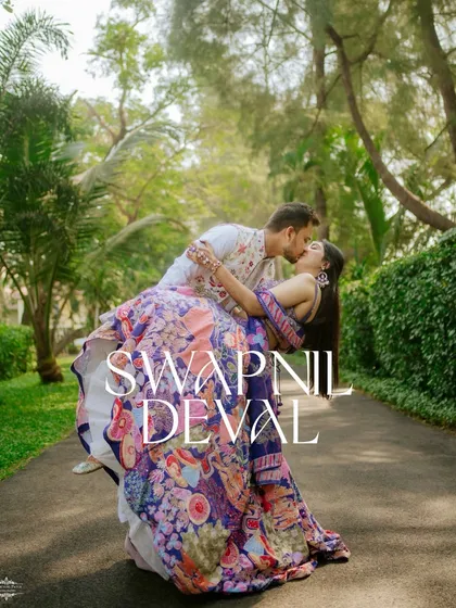A dynamic, romantic portrait from a pre-wedding shoot in Goa. The vibrant colors of their traditional outfits look stunning against the lush greenery of the resort.