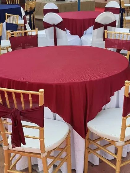 This image showcases another option for formal event seating. The combination of maroon and navy blue tablecloths with gold Chiavari chairs provides a bold and regal color palette, perfect for awards ceremonies or milestone celebrations.