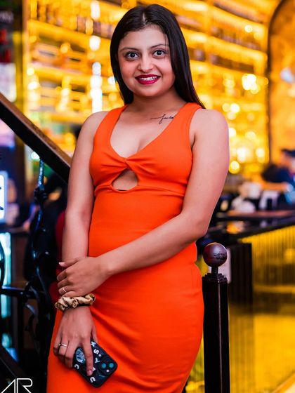 A guest posing in an orange dress.
