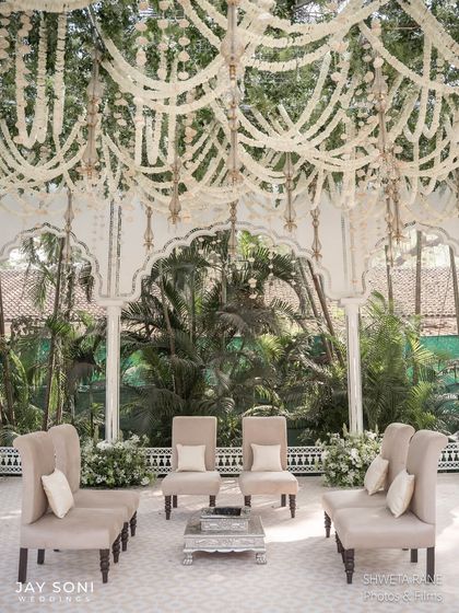 The mandap seating area, featuring elegant high-backed chairs arranged under a ceiling of cascading white floral garlands, creating a serene and beautiful space for the family.