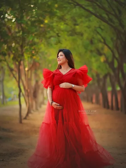 A beautiful outdoor portrait in a vibrant red tulle gown. The natural setting and the elegance of the dress create a striking contrast.