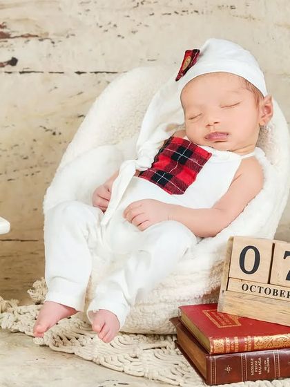A newborn sleeps in a miniature armchair, with a calendar block showing the date. A wonderful way to commemorate the exact day of the photoshoot.